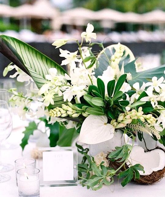 chic wedding centerpiece with tropical leaves coconuts and orchids