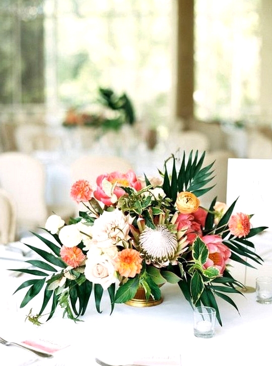 tropical wedding centerpiece with palm leaves, protea and peony